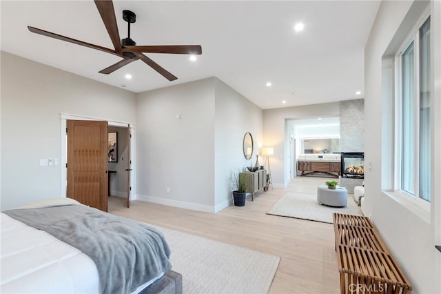 bedroom featuring light hardwood / wood-style flooring, a multi sided fireplace, and ceiling fan