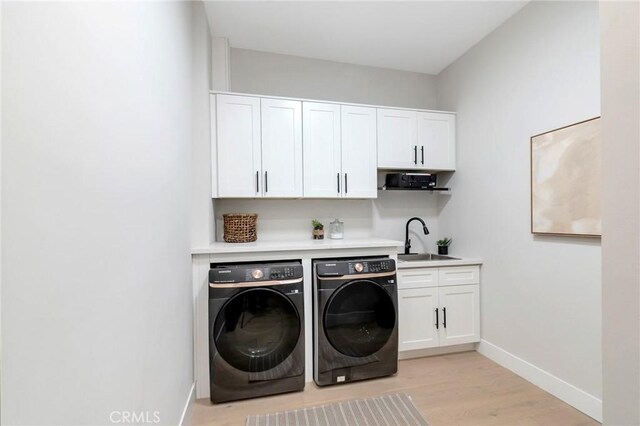 clothes washing area featuring light wood-type flooring, separate washer and dryer, and sink