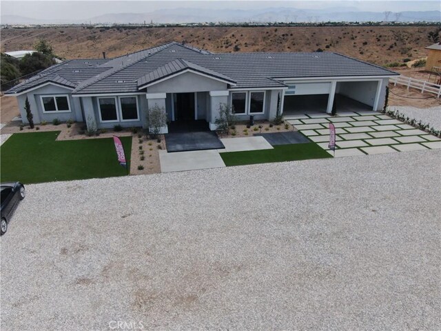 ranch-style house featuring a front yard, a mountain view, and a garage