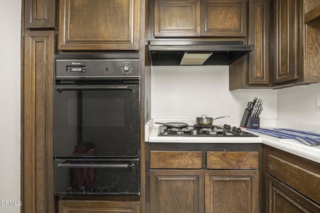 kitchen featuring stainless steel gas stovetop, dark brown cabinetry, and range hood