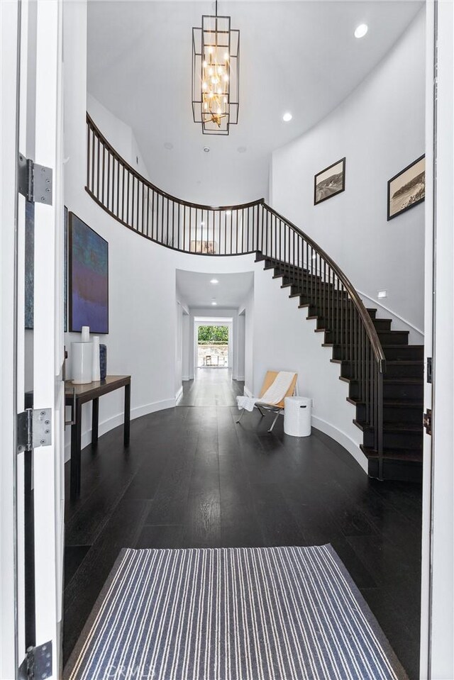 entrance foyer with a towering ceiling, dark hardwood / wood-style flooring, and a notable chandelier