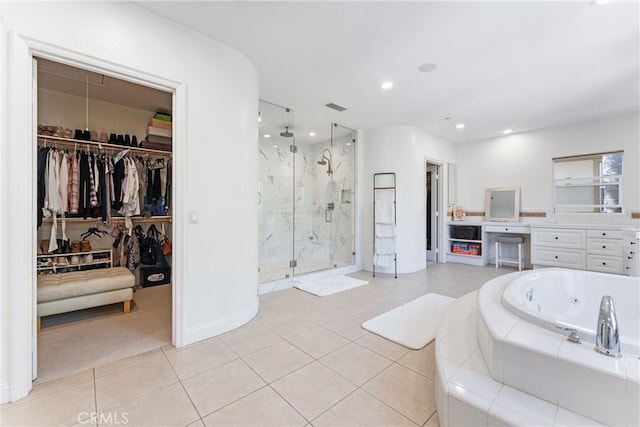 bathroom with tile patterned flooring, vanity, a spacious closet, a jetted tub, and a marble finish shower