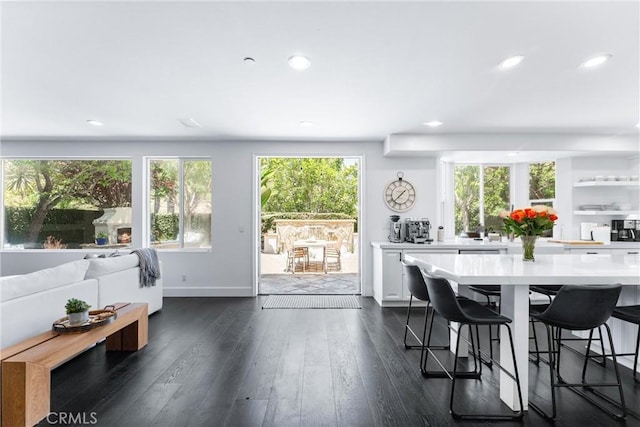 kitchen featuring recessed lighting, light countertops, dark wood-type flooring, white cabinets, and a kitchen breakfast bar