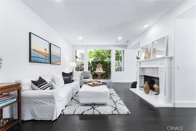 living area featuring baseboards, dark wood-type flooring, a glass covered fireplace, and recessed lighting