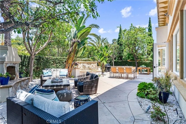 view of patio with an outdoor living space with a fireplace and outdoor dining area