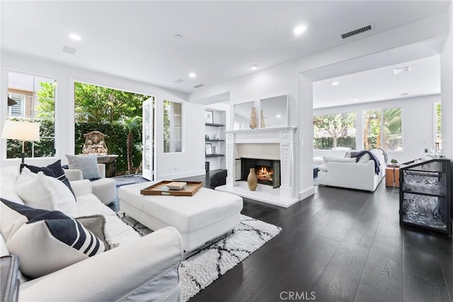 living area with dark wood-type flooring, a premium fireplace, visible vents, and recessed lighting