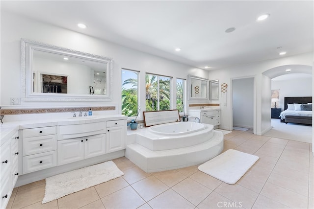 bathroom with connected bathroom, a tub with jets, tile patterned floors, two vanities, and recessed lighting