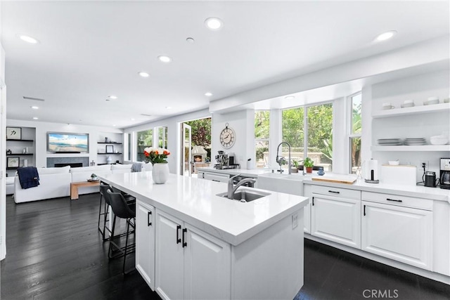 kitchen with an island with sink, white cabinetry, a sink, and recessed lighting