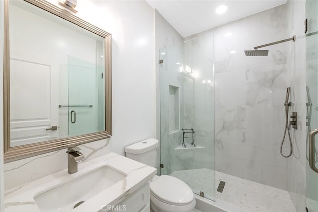 bathroom featuring vanity, a shower with shower door, and toilet