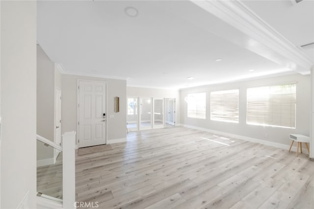 unfurnished living room with a wealth of natural light, crown molding, and light hardwood / wood-style flooring