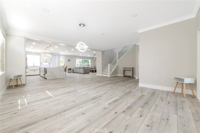 unfurnished living room featuring sink, ornamental molding, a chandelier, and light wood-type flooring