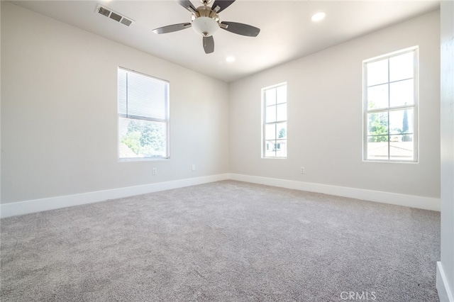 carpeted empty room with ceiling fan and a wealth of natural light