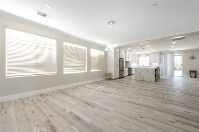 unfurnished living room featuring ornamental molding, sink, and light wood-type flooring