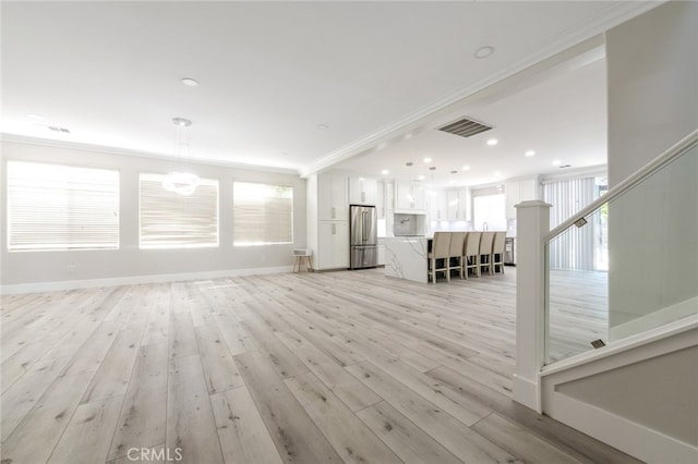 unfurnished living room featuring ornamental molding and light hardwood / wood-style floors