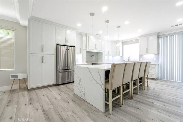 4806 W Concord Ave, Visalia, CA 93277 - kitchen featuring high quality fridge, a kitchen island, light wood finished floors, white cabinetry, and a kitchen breakfast bar