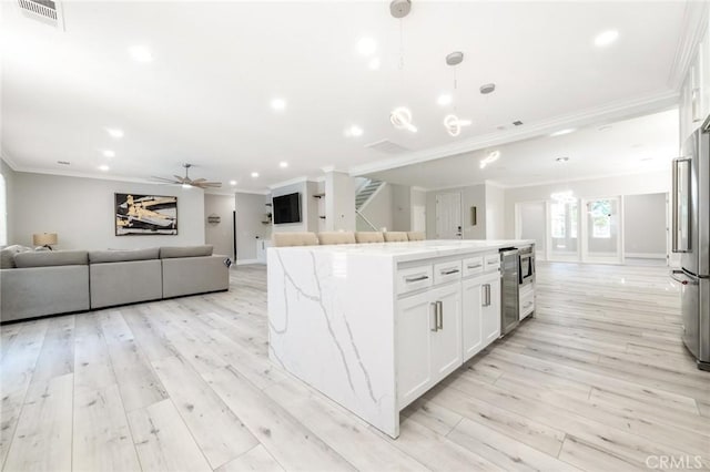 4806 W Concord Ave, Visalia, CA 93277 - kitchen featuring ornamental molding, open floor plan, white cabinets, a center island, and light wood-style flooring