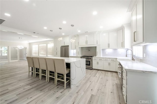 4806 W Concord Ave, Visalia, CA 93277 - kitchen with high end appliances, a sink, light wood-style floors, a center island, and tasteful backsplash