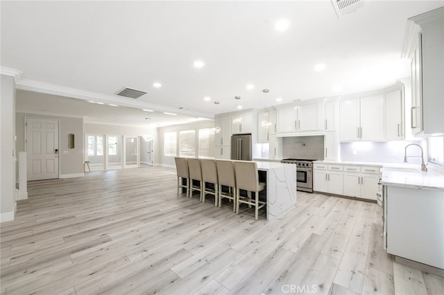 kitchen with a kitchen island, ornamental molding, sink, premium appliances, and light hardwood / wood-style floors