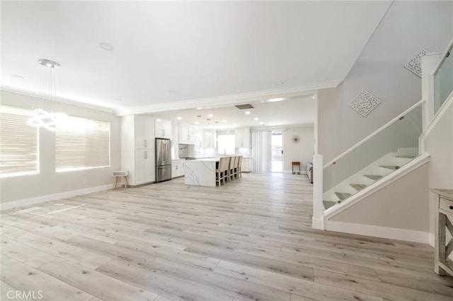 4806 W Concord Ave, Visalia, CA 93277 - unfurnished living room with a chandelier, stairs, light wood-style floors, ornamental molding, and baseboards