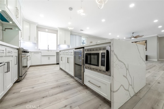 kitchen with appliances with stainless steel finishes, light wood-type flooring, and white cabinets