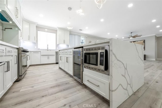 4806 W Concord Ave, Visalia, CA 93277 - kitchen with ornamental molding, appliances with stainless steel finishes, wine cooler, a sink, and white cabinetry