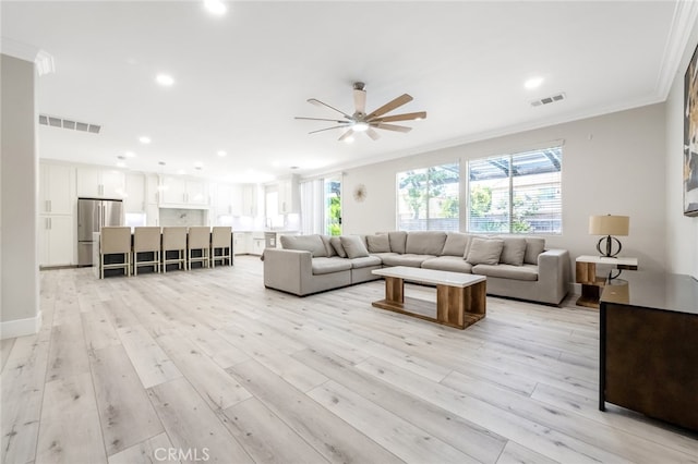 living room with crown molding, light wood-type flooring, and ceiling fan