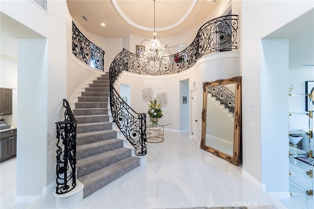 foyer entrance with a towering ceiling, a raised ceiling, and a chandelier