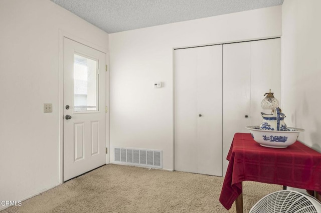 interior space with a closet, a textured ceiling, and light colored carpet