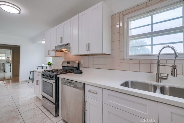 kitchen with decorative backsplash, white cabinetry, sink, and appliances with stainless steel finishes