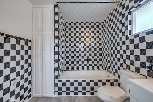 bathroom with toilet, vanity, tile walls, and hardwood / wood-style flooring