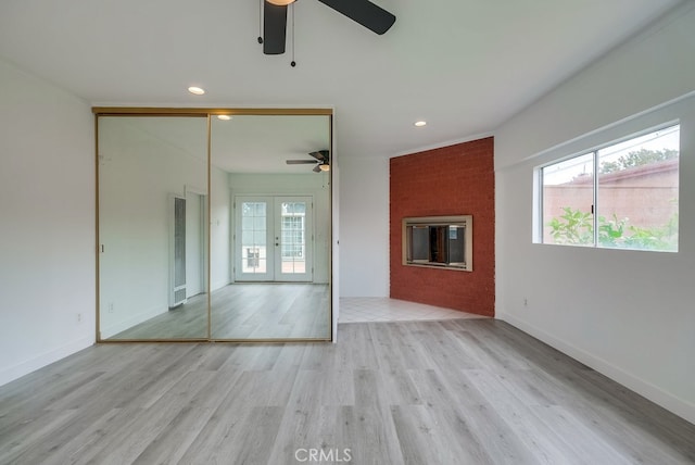 unfurnished living room featuring a wealth of natural light, french doors, ceiling fan, and light hardwood / wood-style flooring