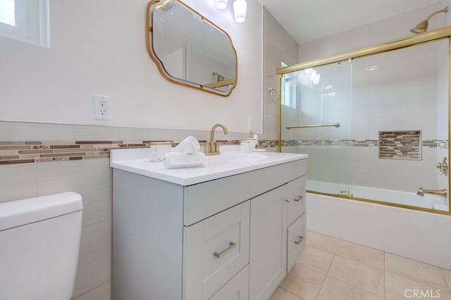 full bathroom with vanity, shower / bath combination with glass door, tile patterned floors, toilet, and tile walls