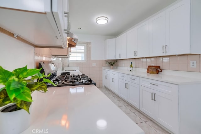 kitchen featuring white cabinets, light tile patterned floors, stove, and tasteful backsplash