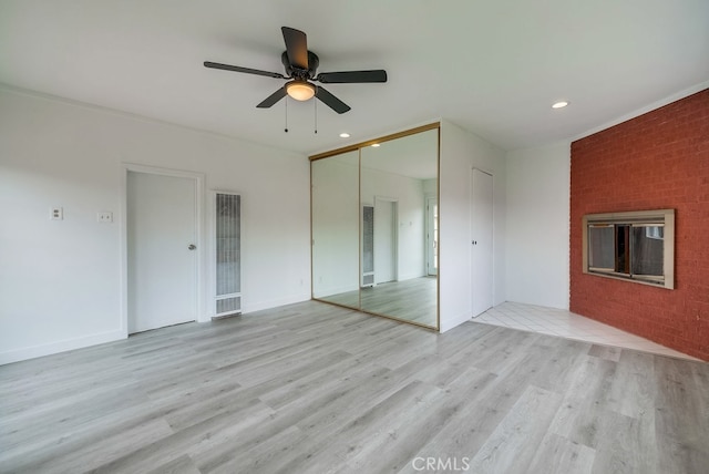 spare room featuring a fireplace, ceiling fan, light hardwood / wood-style flooring, and crown molding