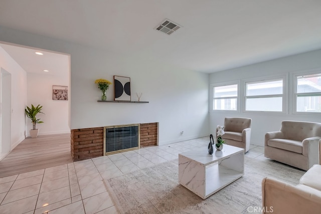 living room featuring light wood-type flooring and a brick fireplace