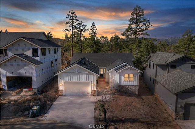 view of front of house featuring board and batten siding, stone siding, concrete driveway, and a garage