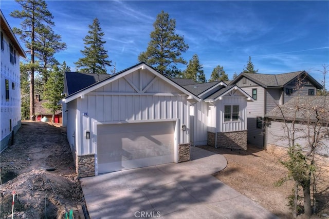 view of front of property featuring board and batten siding, stone siding, driveway, and an attached garage