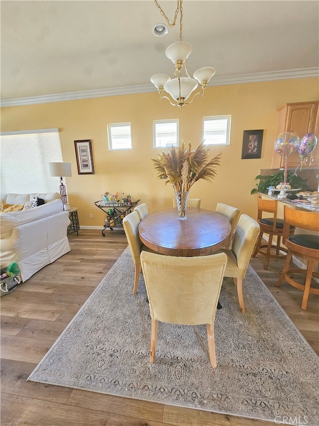 dining area featuring light hardwood / wood-style flooring, ornamental molding, and a notable chandelier