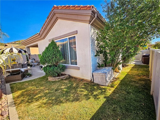 rear view of property featuring a patio area, stucco siding, a fenced backyard, and a lawn