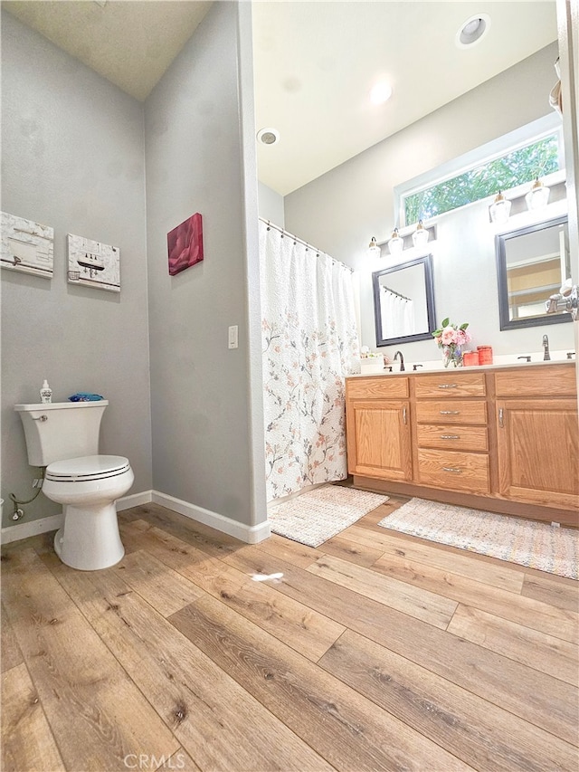 bathroom with a shower with shower curtain, hardwood / wood-style floors, vanity, and toilet