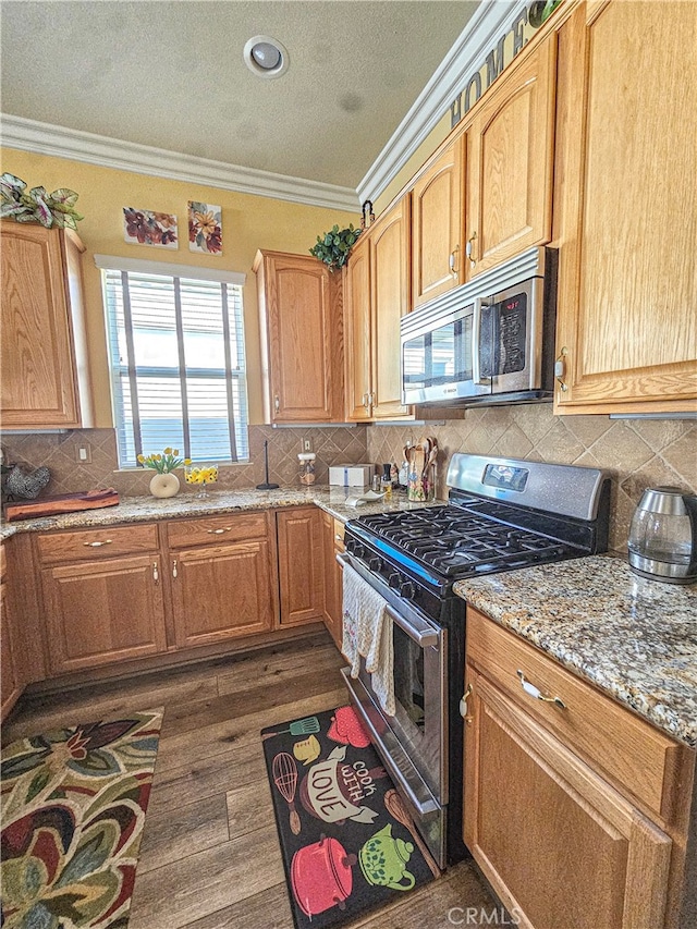 kitchen with crown molding, light stone counters, dark hardwood / wood-style flooring, and stainless steel appliances