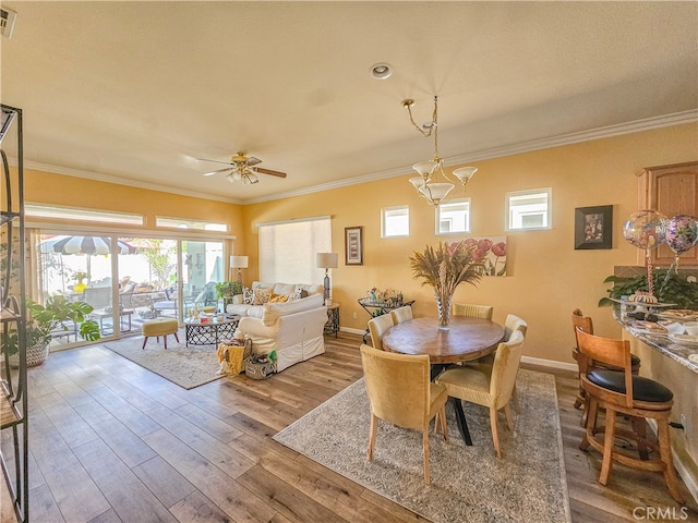 dining room with wood-type flooring, crown molding, and a healthy amount of sunlight