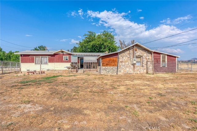 view of front of home featuring stone siding, cooling unit, and fence