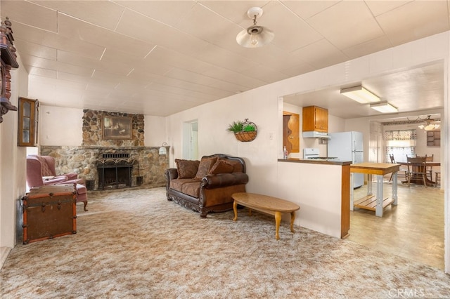 living room with carpet floors and a stone fireplace