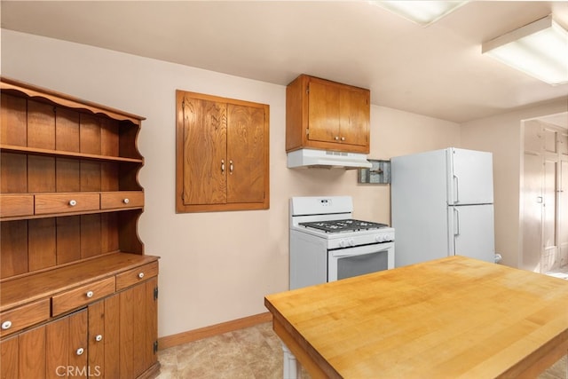 kitchen with white appliances, baseboards, brown cabinets, under cabinet range hood, and wooden counters