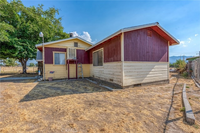 view of front of home with crawl space and fence