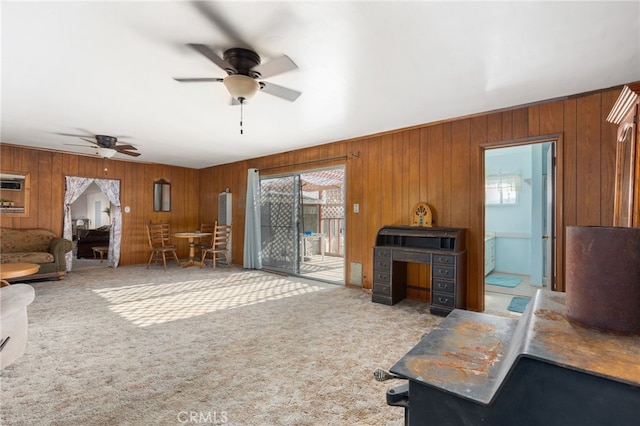 living room with carpet floors, wood walls, and a ceiling fan