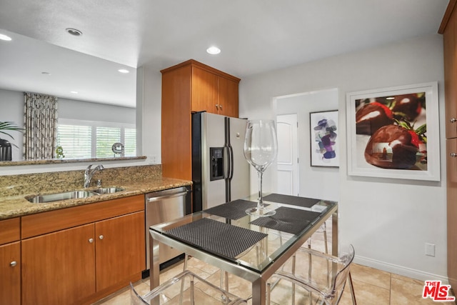 kitchen featuring light stone counters, sink, light tile patterned floors, and appliances with stainless steel finishes