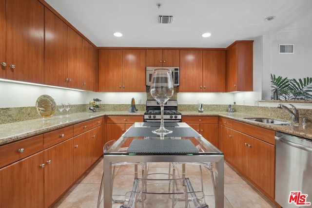 kitchen featuring light stone counters, sink, light tile patterned floors, and stainless steel appliances