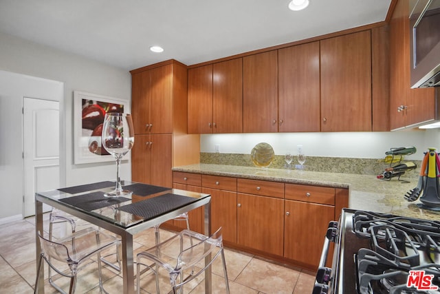 kitchen featuring light stone countertops, light tile patterned flooring, and appliances with stainless steel finishes